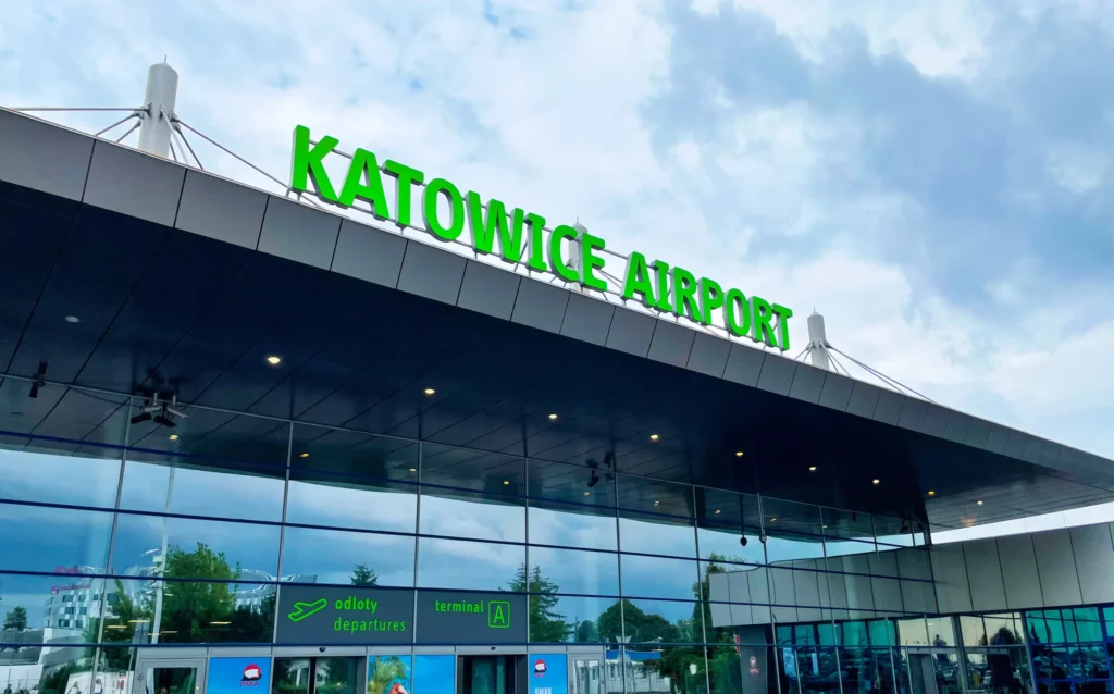 Zielony podświetlany napis "KATOWICE AIRPORT" na dachu budynku lotniska.